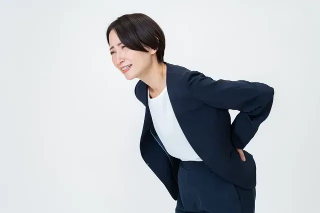 腰をおさえてつらそうな女性
